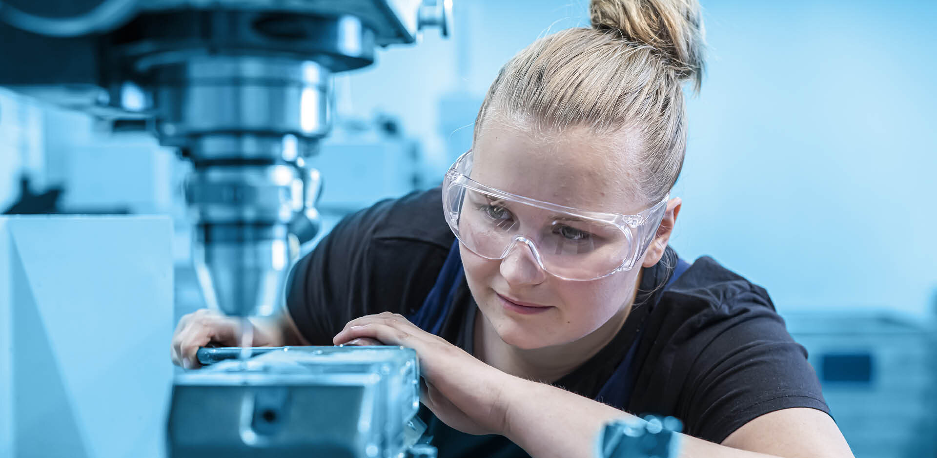 Mitarbeiterin mit Schutzbrille an der Bohrmaschine | Sandler Group