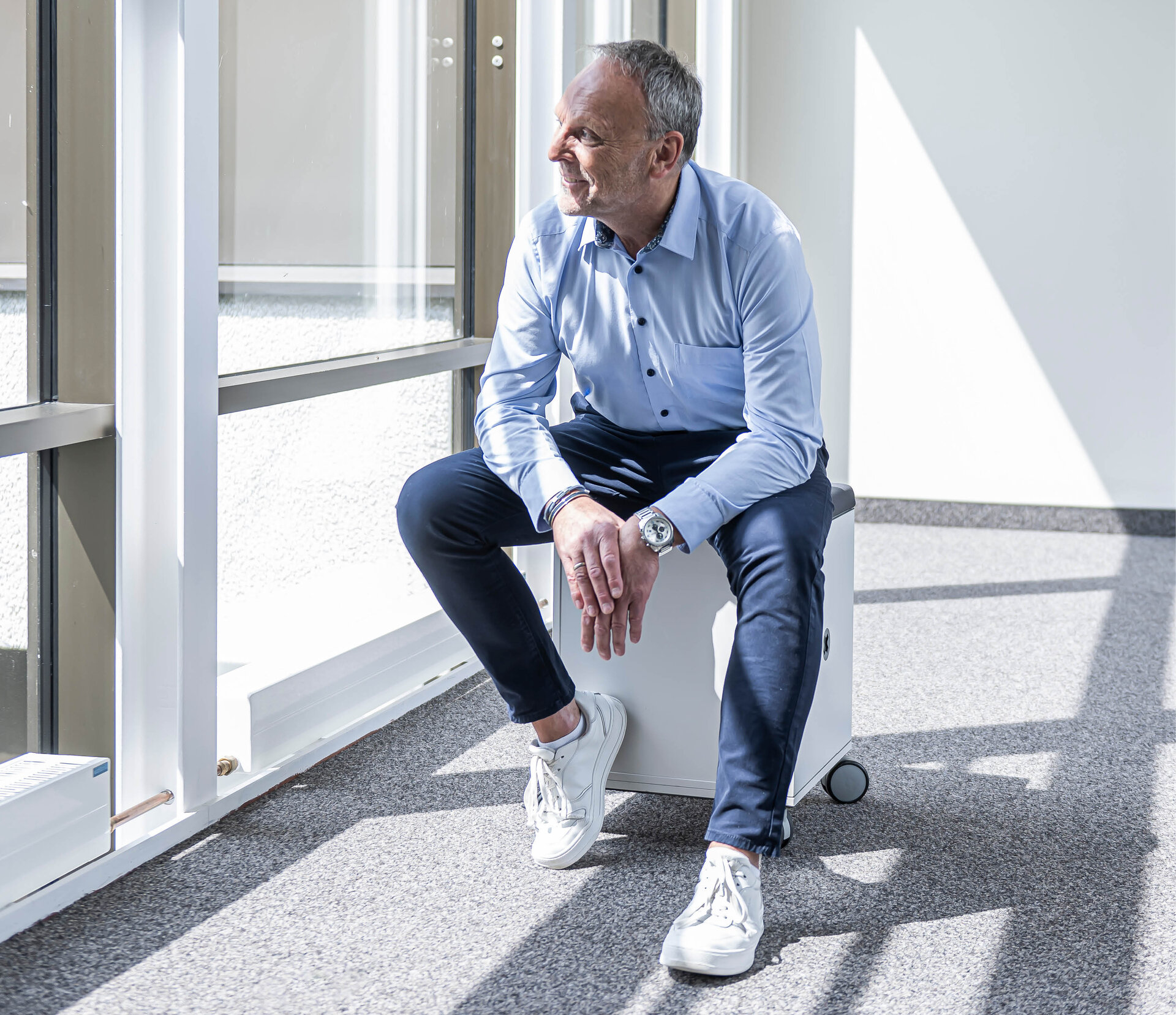 Man sitting on a stool in front of a window | Sandler Group 